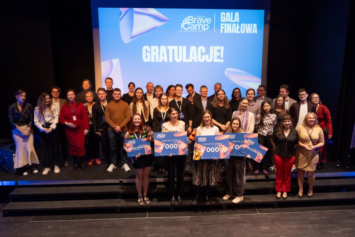 A large group of people standing on stage, including students awarded in the BraveCamp finals