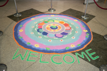 Kolam which is a symmetrical pattern strewn with salt. It has a round shape in blue, blue, sea, pink colors. 