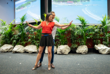 Dancing couple. The girl is dancing in front. She is dressed in a red blouse and black skirt. Behind her is a boy in a white shirt and jeans. 