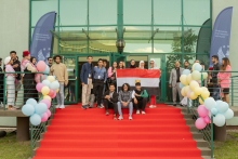 Stairs. On them spread red carpet. On the stairs a large group of people. They are holding the flag of Egypt.