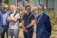 Four men stand side by side. The first and last in blazers. The other two in polo shirts.