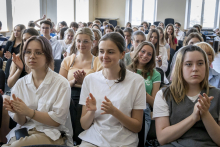 Close-up of young people sitting in the lecture hall. In the foreground are three girls.