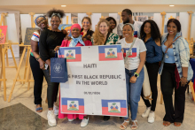 Grupa dziesięciu osób w większości ciemnoskórych trzyma plakat z napisem: Haiti the first black republic in the world