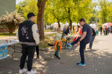 Między stoiskami Mężczyzna podskakuje na jednej nodze obok niego stoi chłopiec.