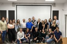 Group photo of students together with lecturers. Six people in the front row are crouching. Behind them stand the other sixteen.