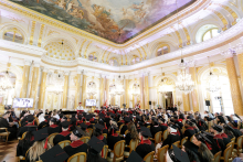 A glimpse of the hall of the Royal Castle in Warsaw and the people in it. They are seated, dressed mostly in black togas and birettas.