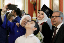 A group of people. One of them holds a mobile phone raised above their heads and takes a picture. 