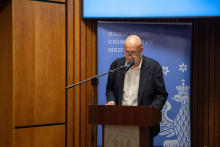 The man on the rostrum speaks into the microphone.