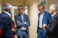 A woman and four men in suits are talking