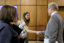 A woman shakes hands with an older man in a suit.