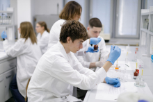 Young people in medical aprons conduct tests in the lab.