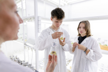 Young people in medical aprons conduct tests in the lab.