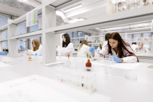 Young people in medical aprons conduct tests in the lab.