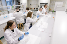 Young people in medical aprons conduct tests in the lab.