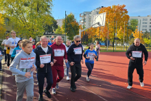 A running group of people dressed in sportswear. They are running on the school field.