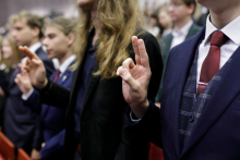 A shot of human hands with the index and middle finger folded in a gesture of pledge.