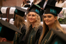 Several people, two of them young women, are smiling at the camera. They are dressed in academic costumes and birettas.