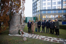 Jedenaście osób stoi w rzędzie przy obelisku z napisem "Ludziom i Ojczyźnie 1809-2009"