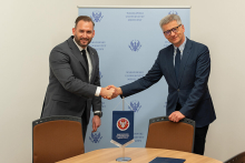 Two elegantly dressed men, shake hands and smile for the camera