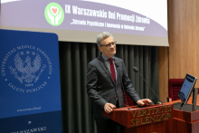 Rektor WUM, mężczyzna w średnim wieku, elegancko ubrany, stoi za mównicą i przemawia.