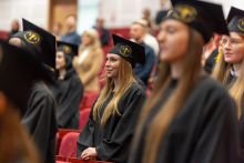 Absolwenci analityki medycznej odebrali dyplomy. Grupa młodych osób, ubranych w czarne togi i birety. Stojąc składają przysięgę.