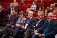 „Aby pasja do nauczania nigdy nie gasła…”. Grupa siedzących osób, patrzą przed siebie.