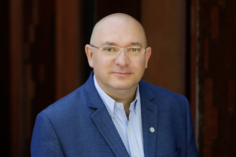 Professor Gałązkowksi, A middle-aged man, with glasses, wearing a navy blue jacket and blue shirt, smiles at the camera