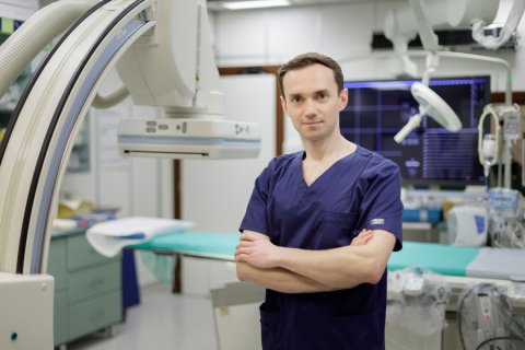 Mariusz Tomaniak, a young man dressed in a doctor's gown stands in a treatment room